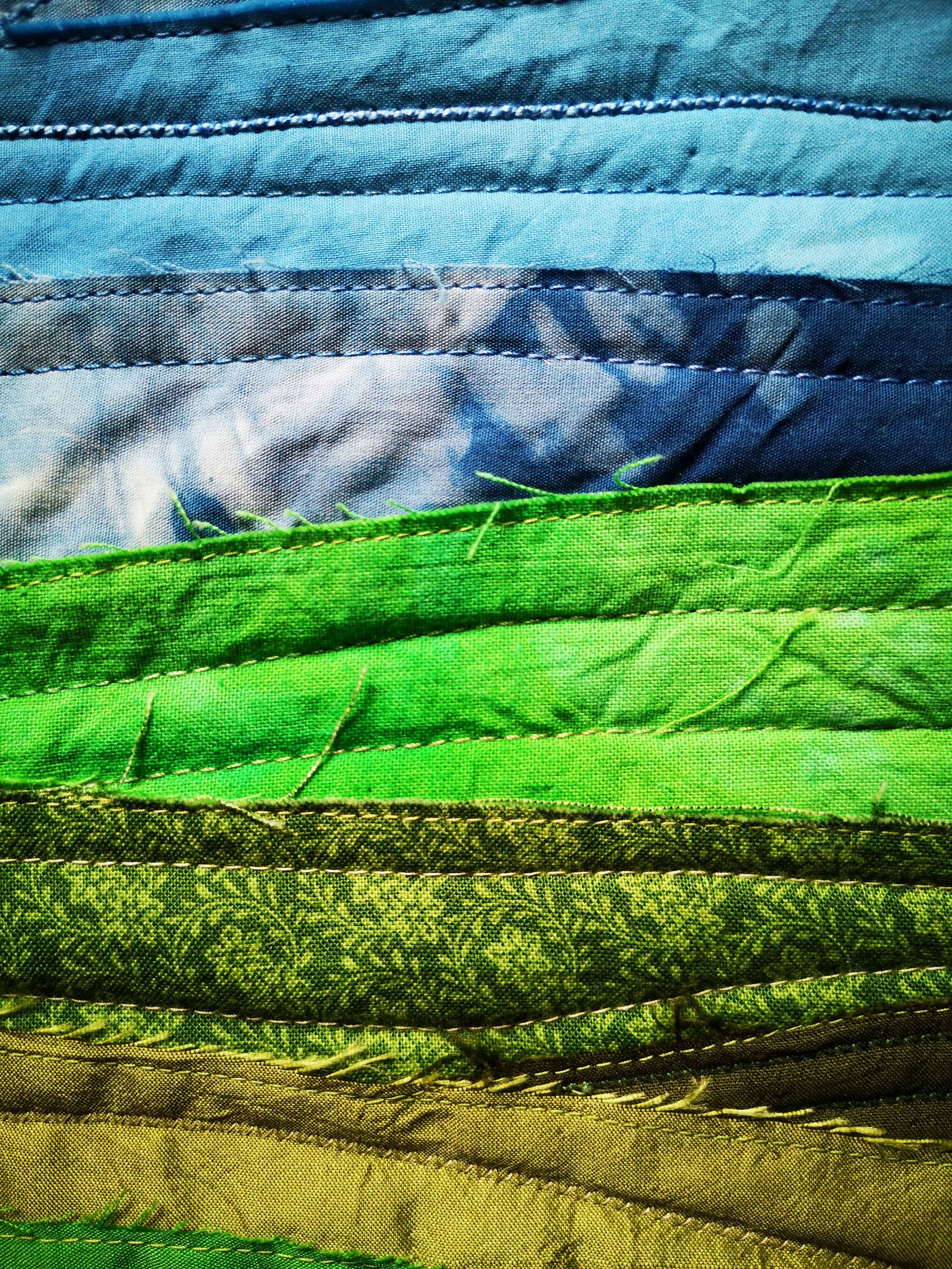 Close-up of textile landscape with blue sky and green fields